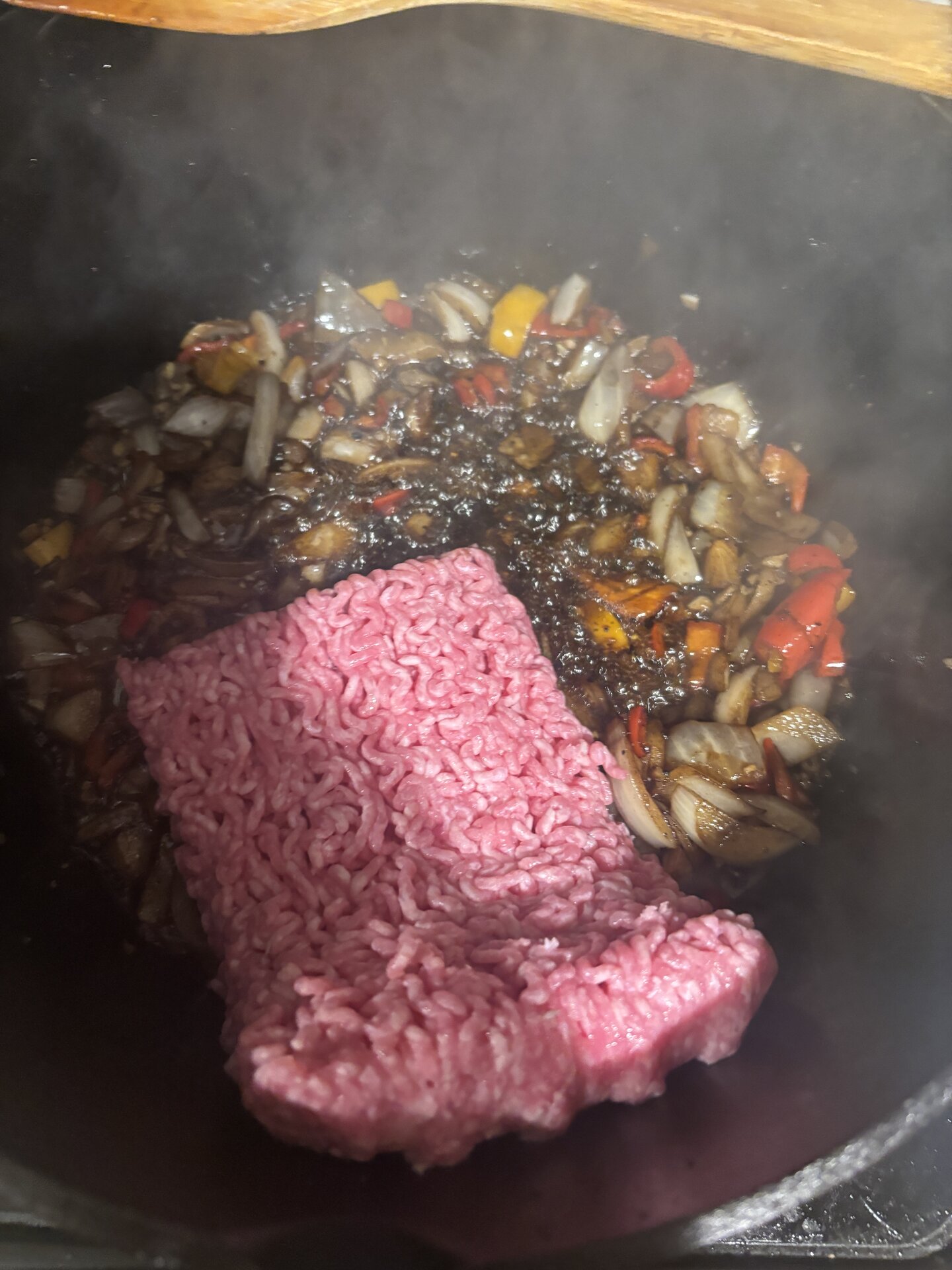 Tomato paste being added to the spiced meat