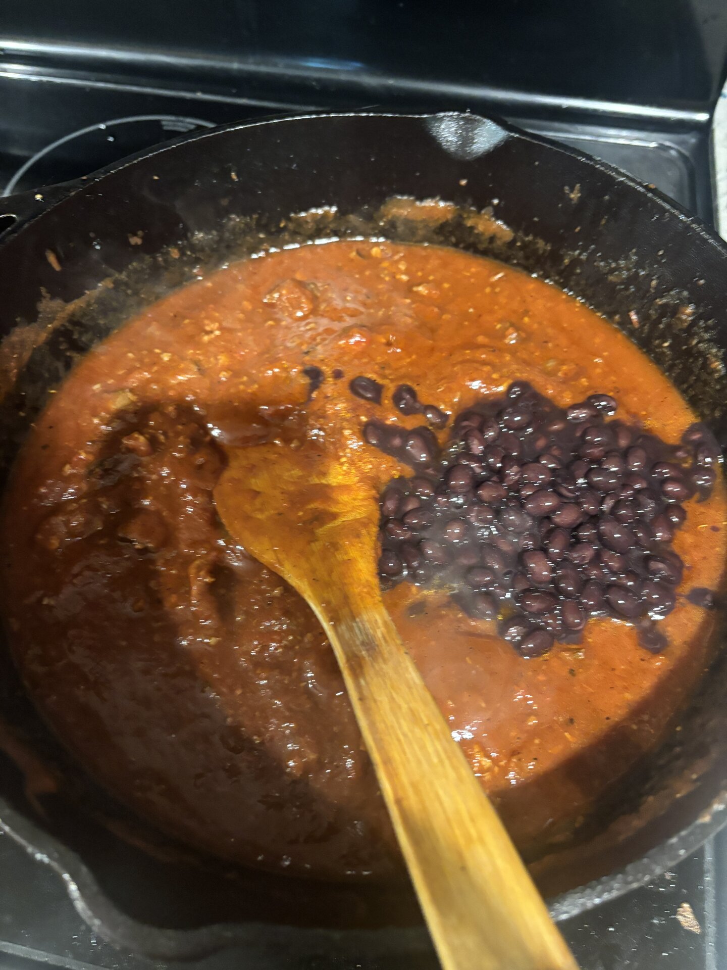 Black beans being stirred into the chili